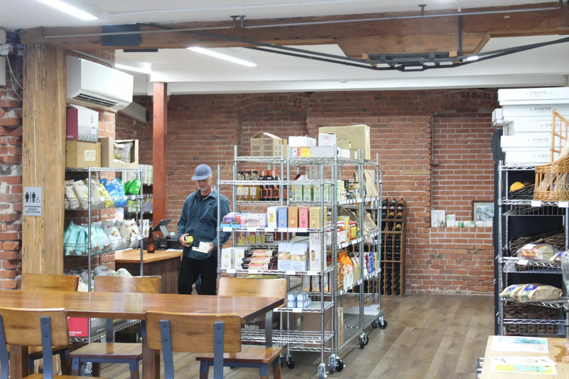 Interior of Olympia Market with shelves of provisions and a customer looking at foods