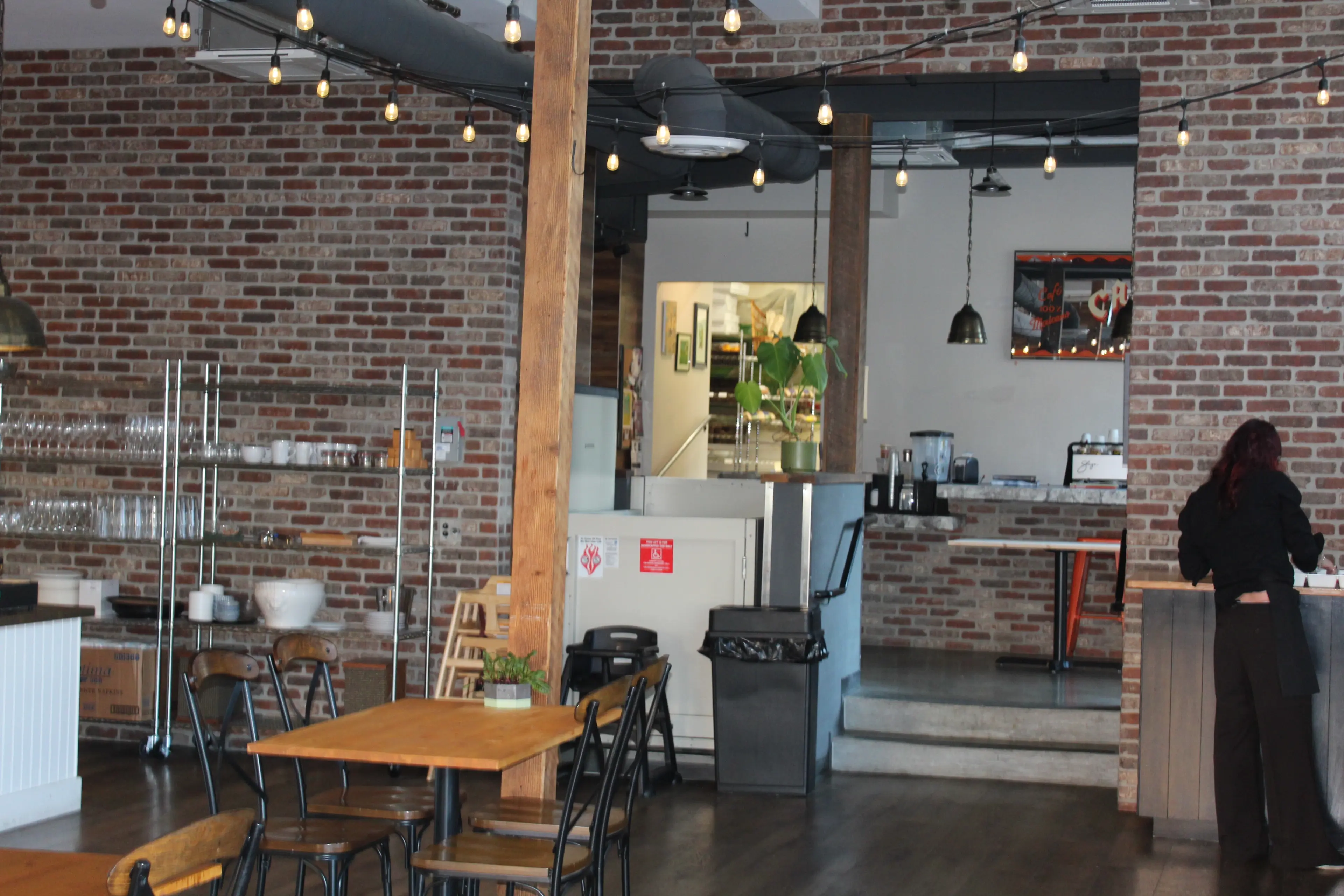The interior of Duke's Dining Hall, showing a brick wall, hanging lights, and tables and chairs.