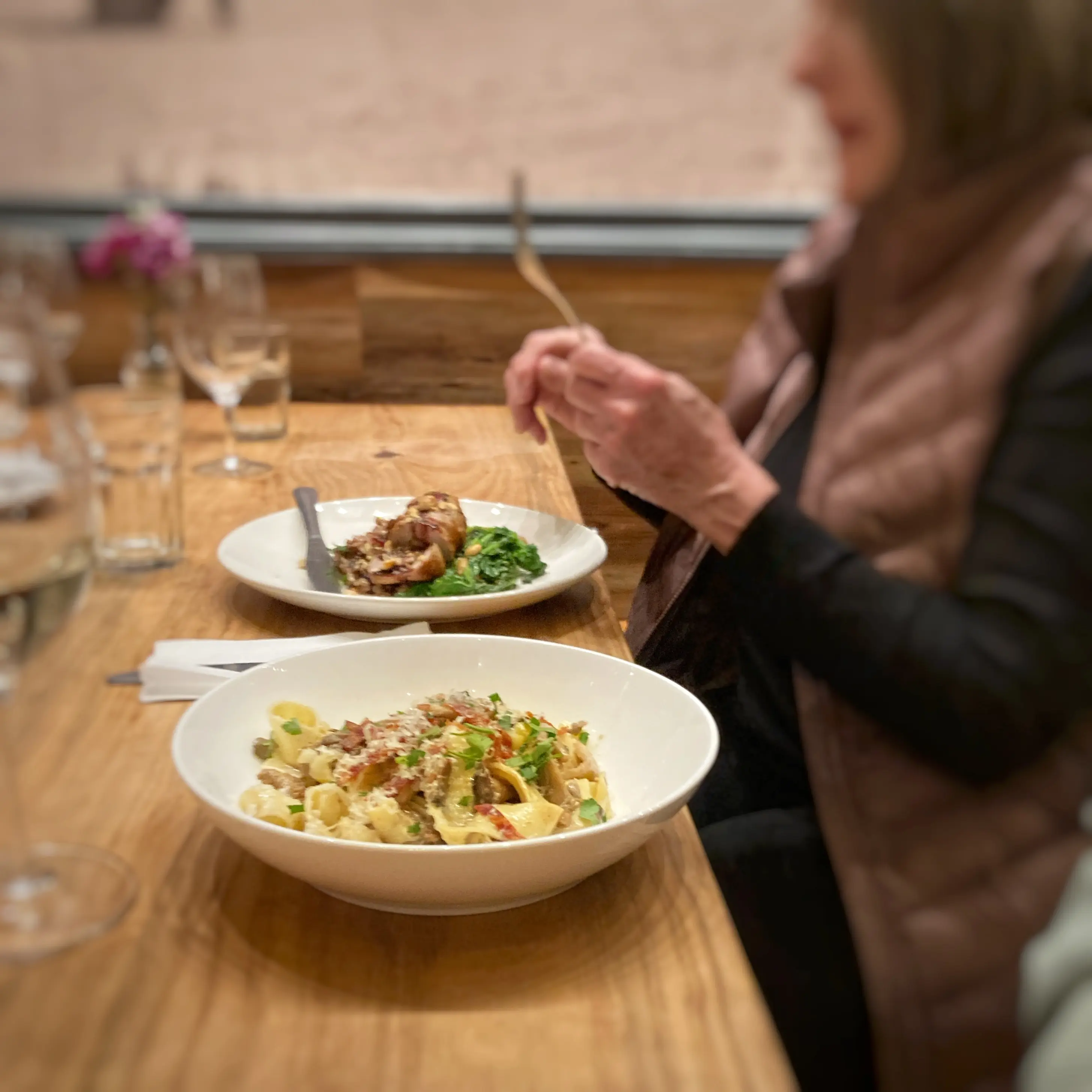 A person sits at a table holding a fork with various dishes of food at Duke's Dining Hall